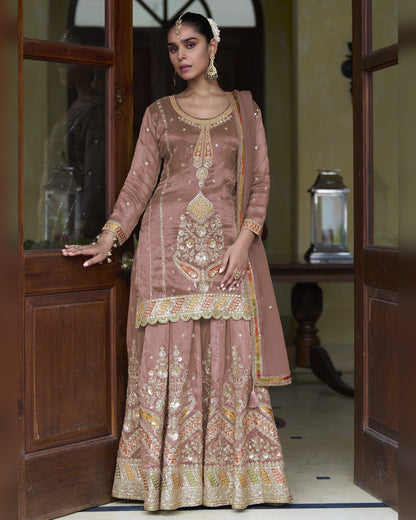 Woman in a traditional embroidered outfit standing in a doorway.