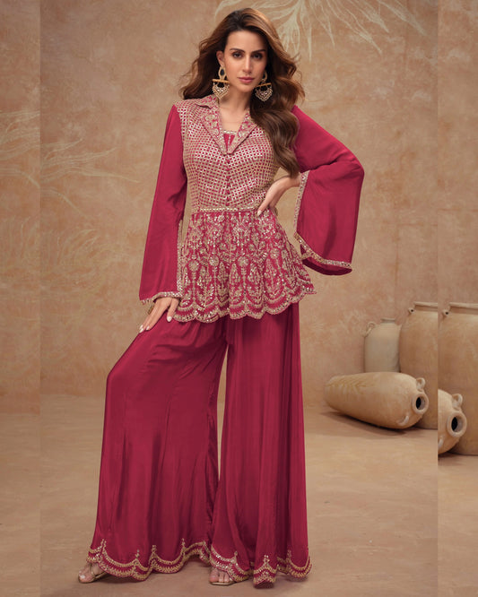 Woman wearing a pink traditional outfit with intricate designs in a beige room.