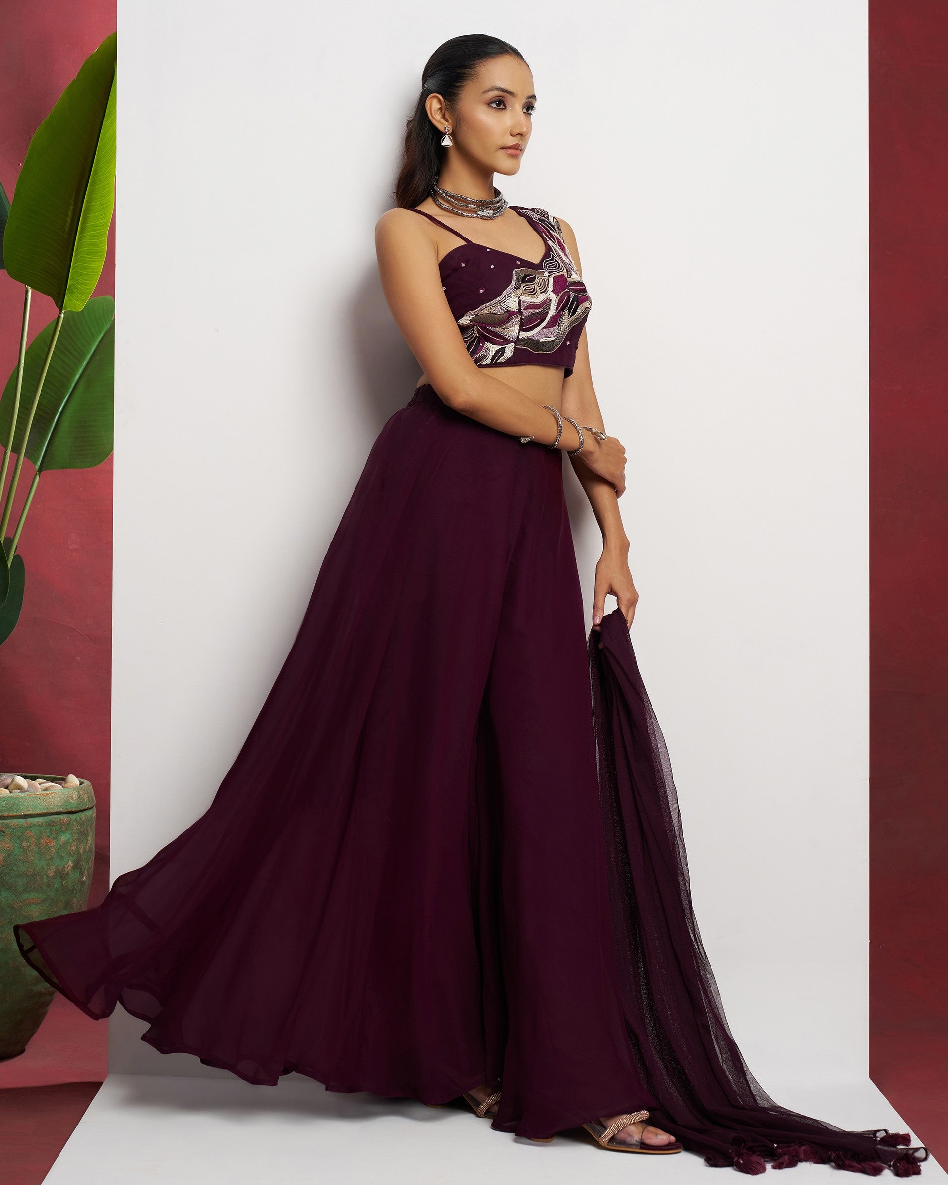 Woman wearing a burgundy evening gown with floral top against a white background