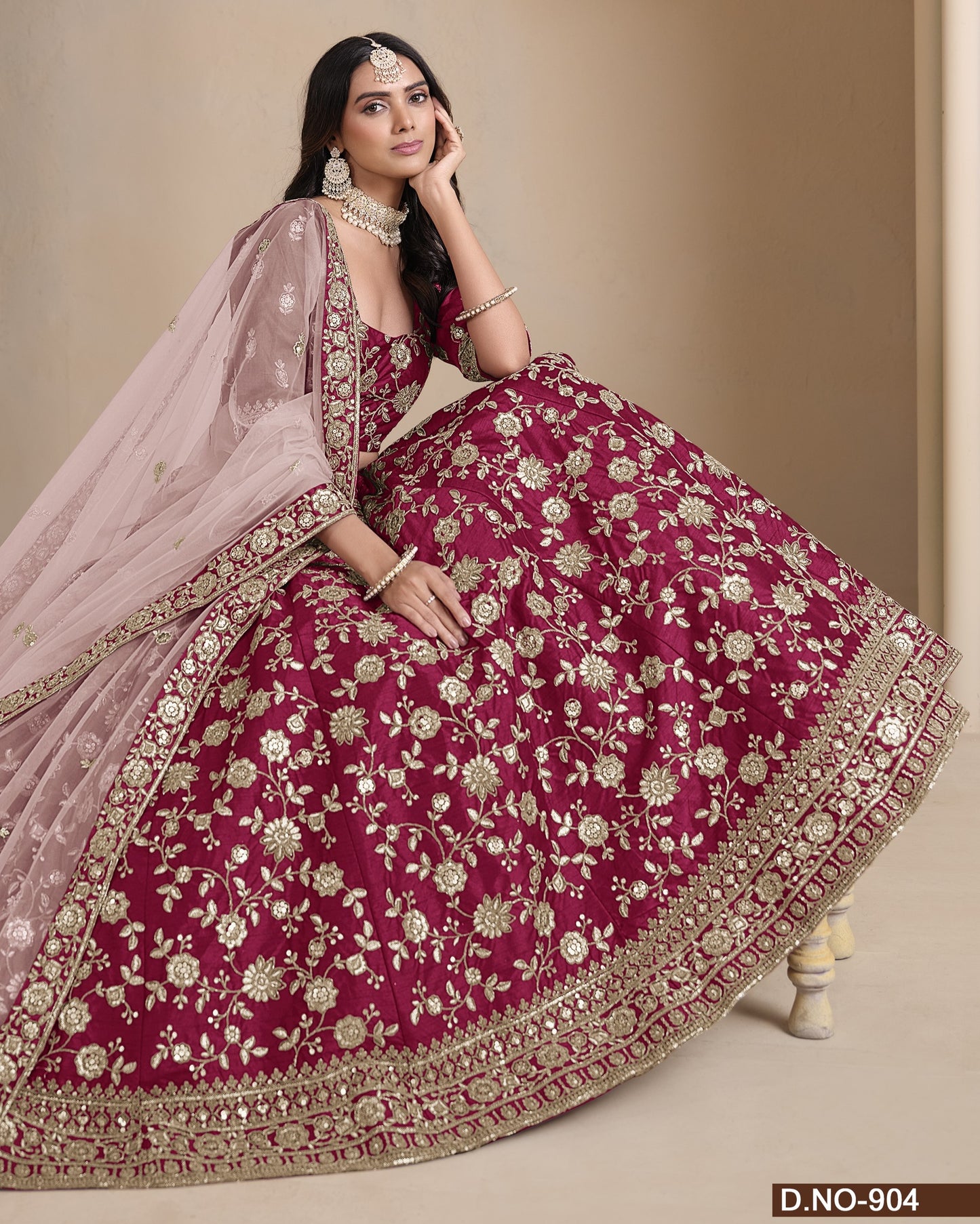 Woman wearing a pink and red embroidered traditional outfit on a beige background