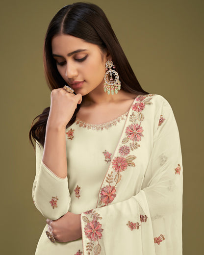 Woman wearing a light green saree with floral embroidery against a brown background