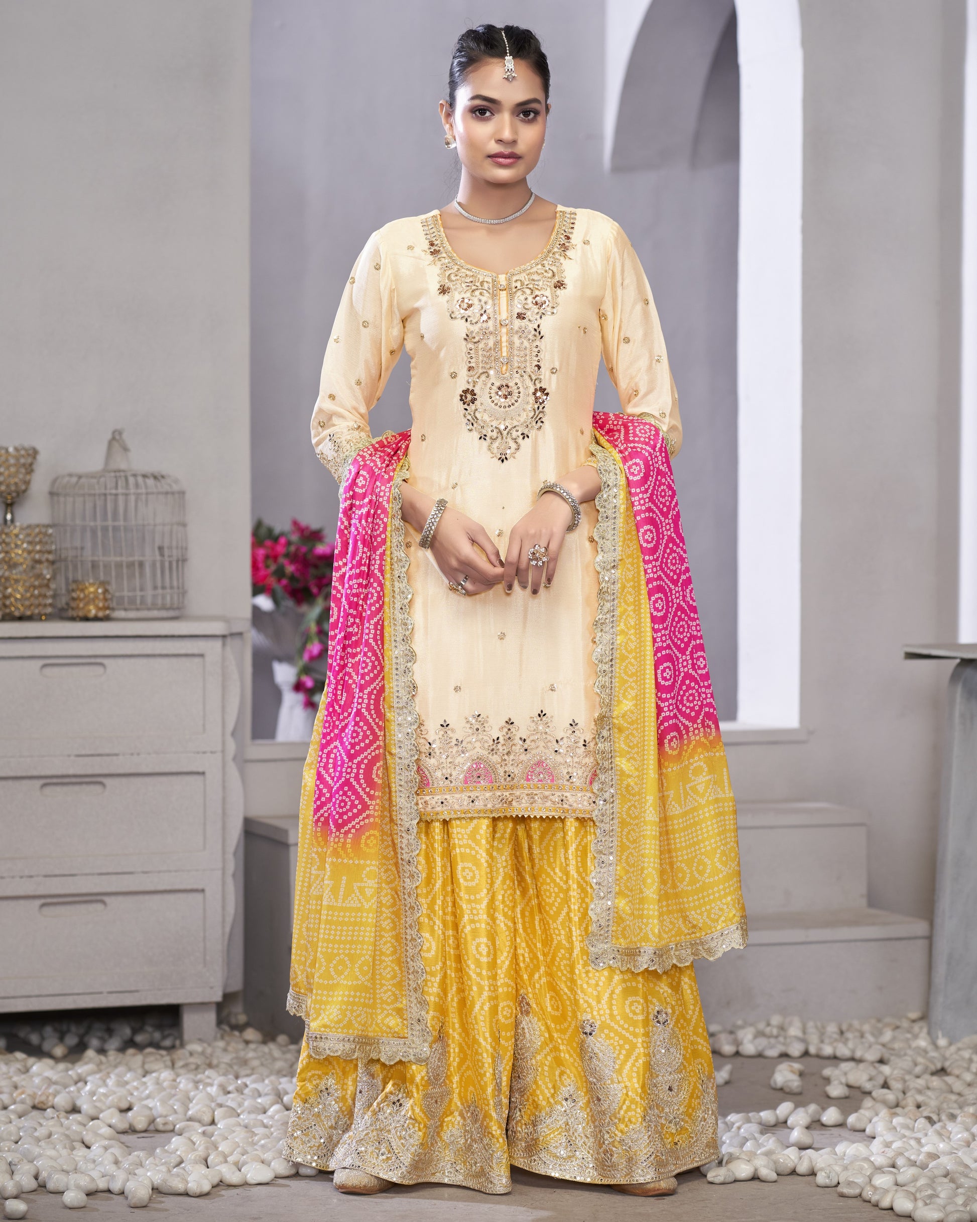 Woman wearing a traditional outfit with a cream top and yellow bottom in a neutral setting.