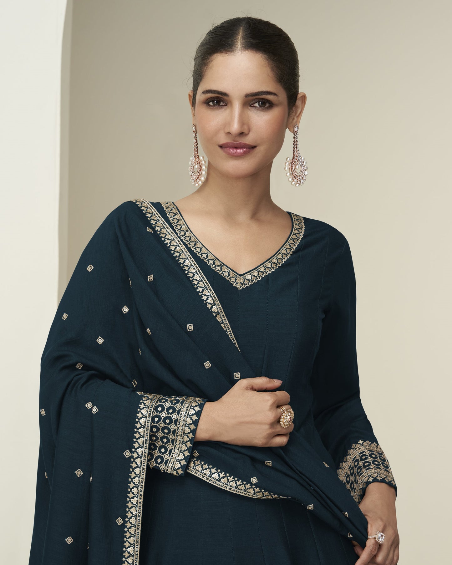 Woman wearing a dark blue embroidered traditional outfit against a neutral background