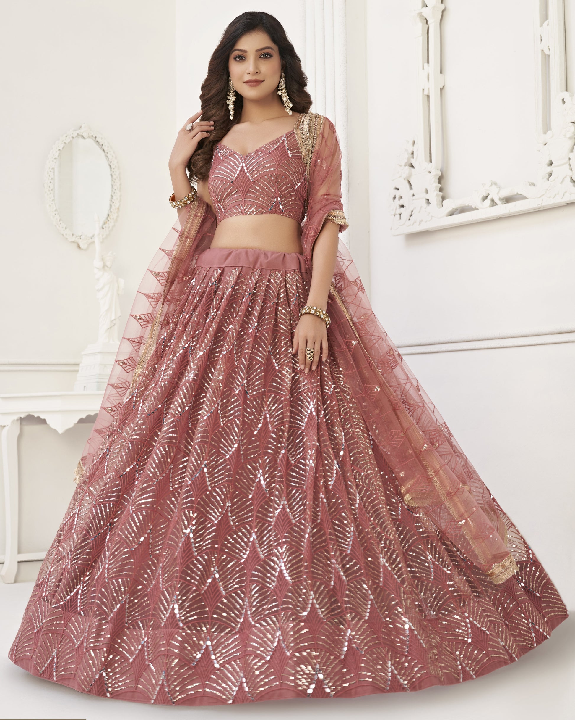 Woman wearing a pink and white embroidered lehenga with a matching blouse.