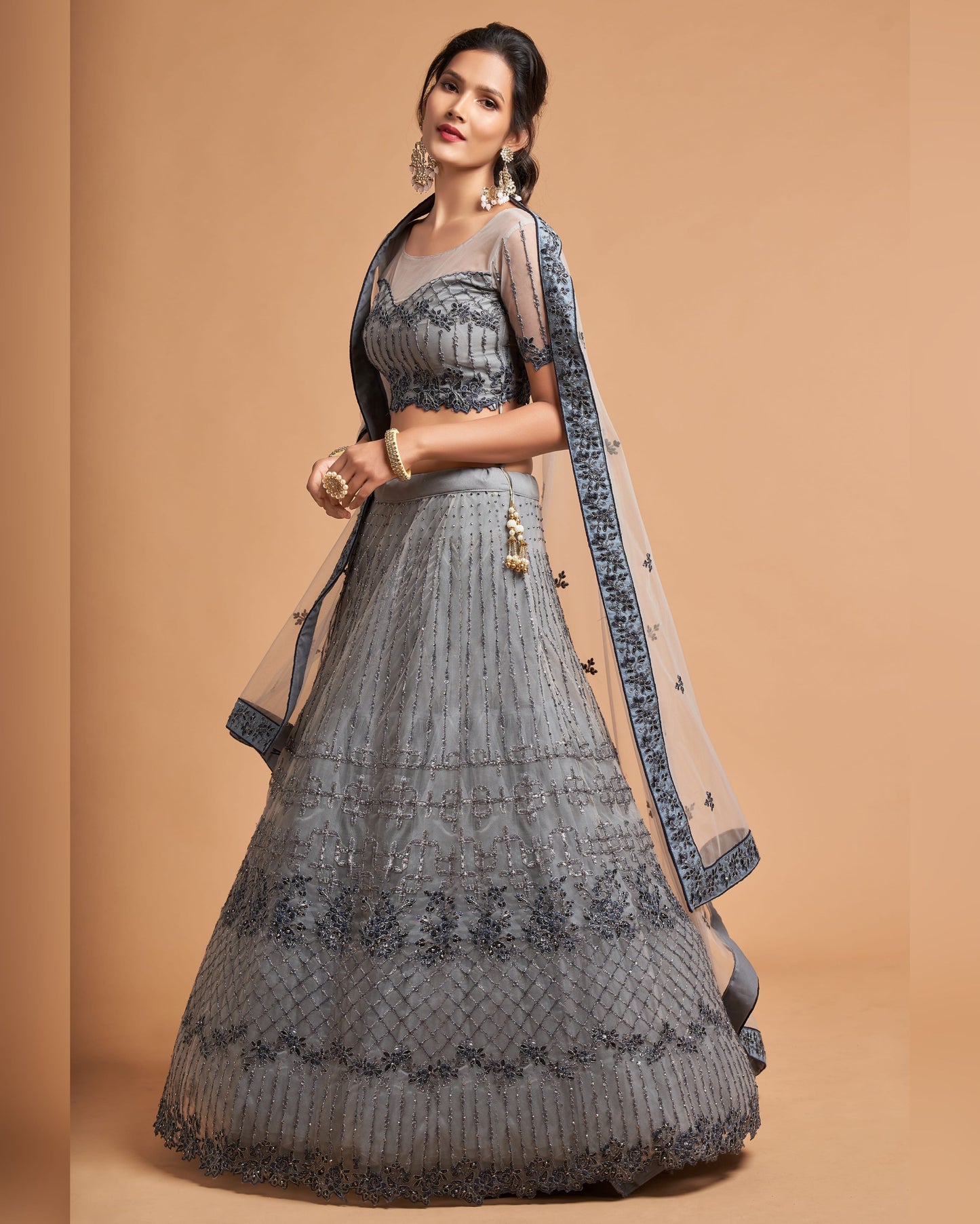 Woman wearing a gray traditional outfit with a beige dupatta on a brown background