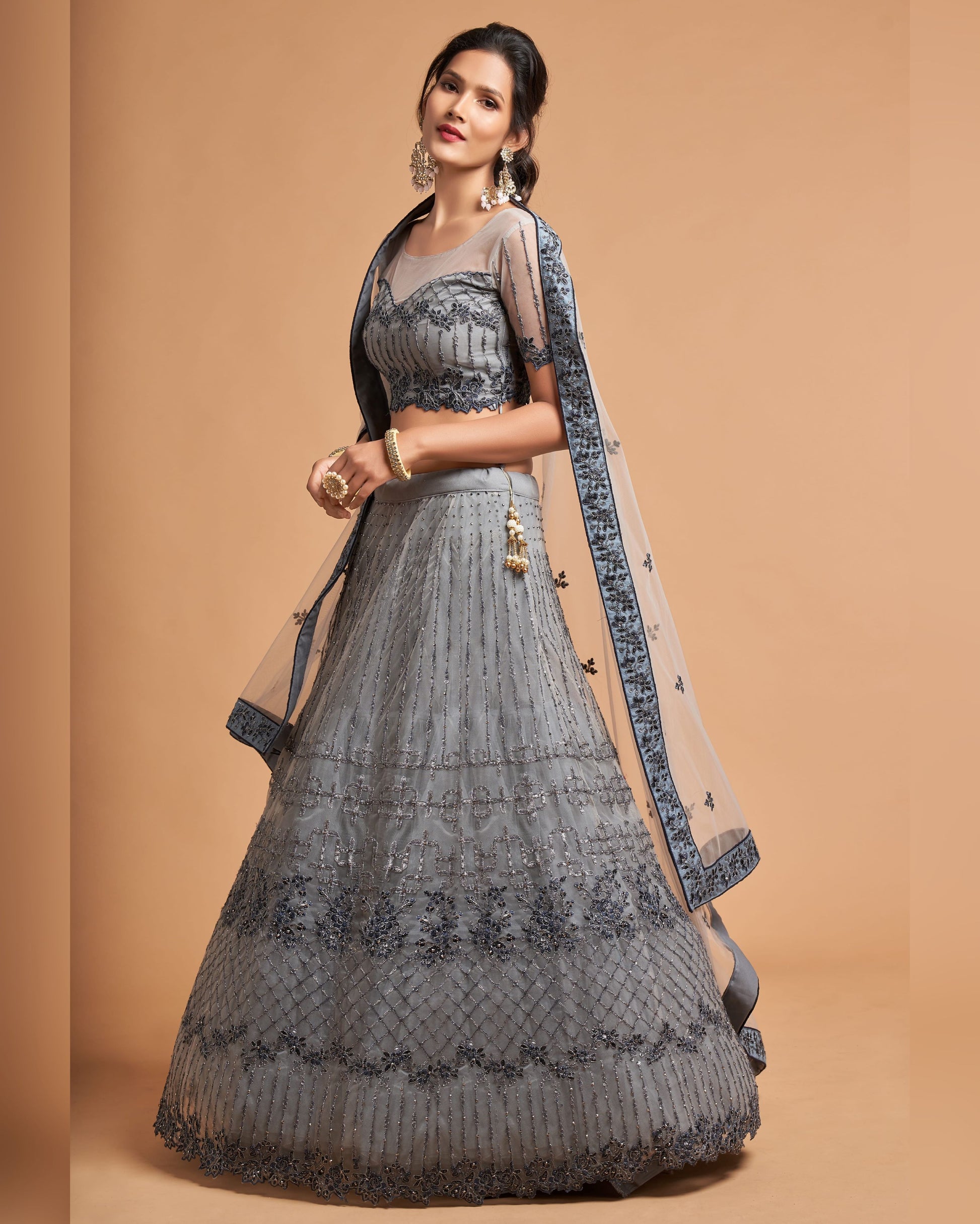 Woman wearing a gray traditional outfit with a beige dupatta on a brown background