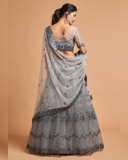 Woman wearing a gray embroidered saree with a beige background