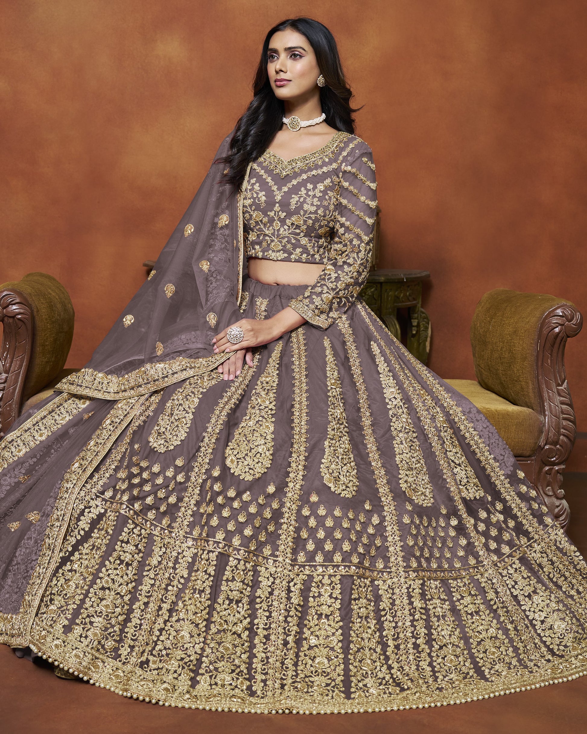 Woman in a traditional embroidered outfit sitting on a brown couch.