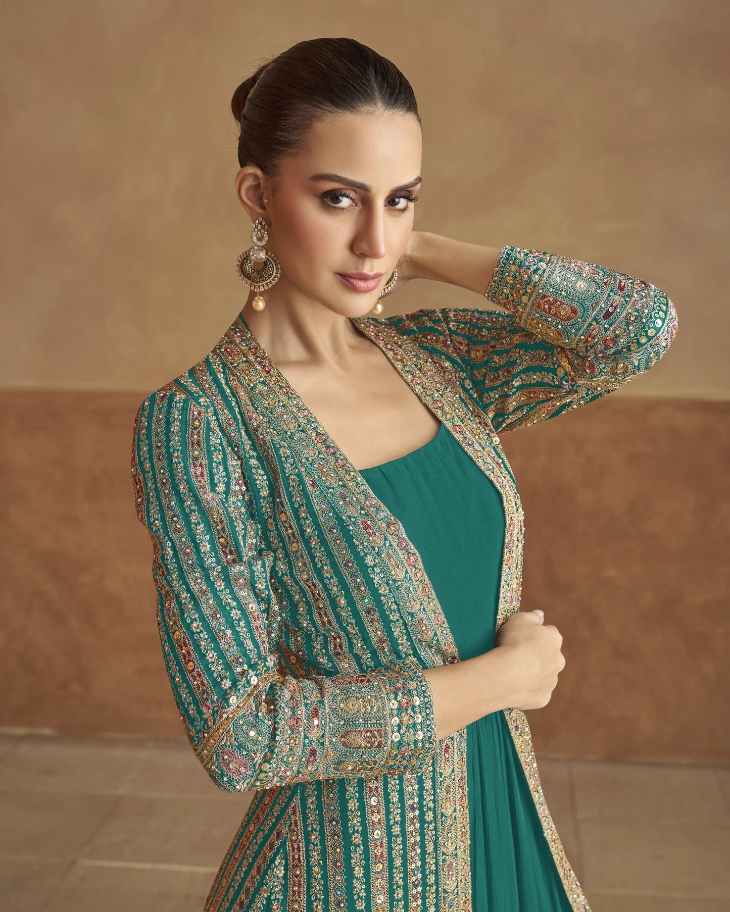 Woman wearing a green traditional outfit with intricate patterns against a beige background