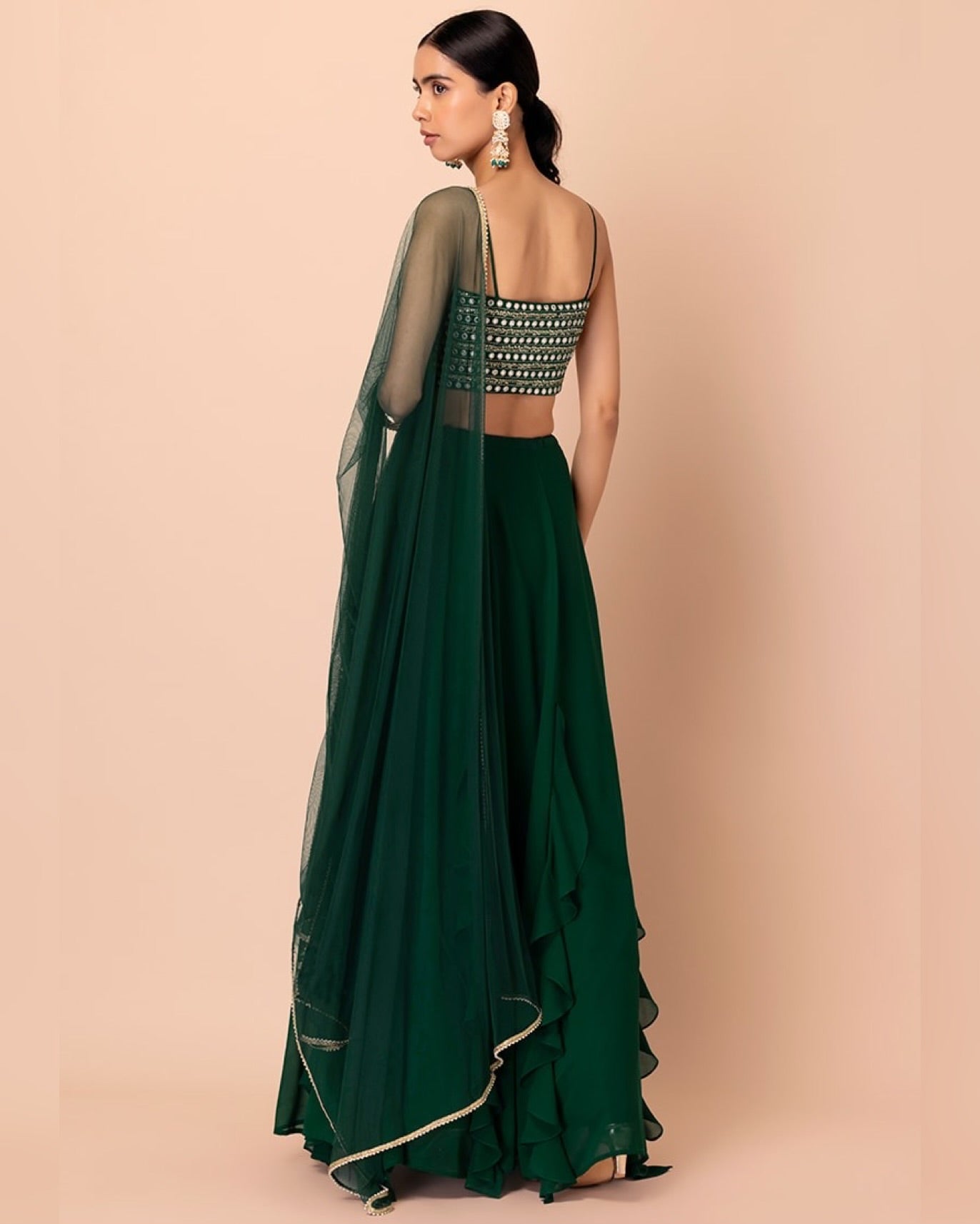 Woman wearing a green saree with a beige background