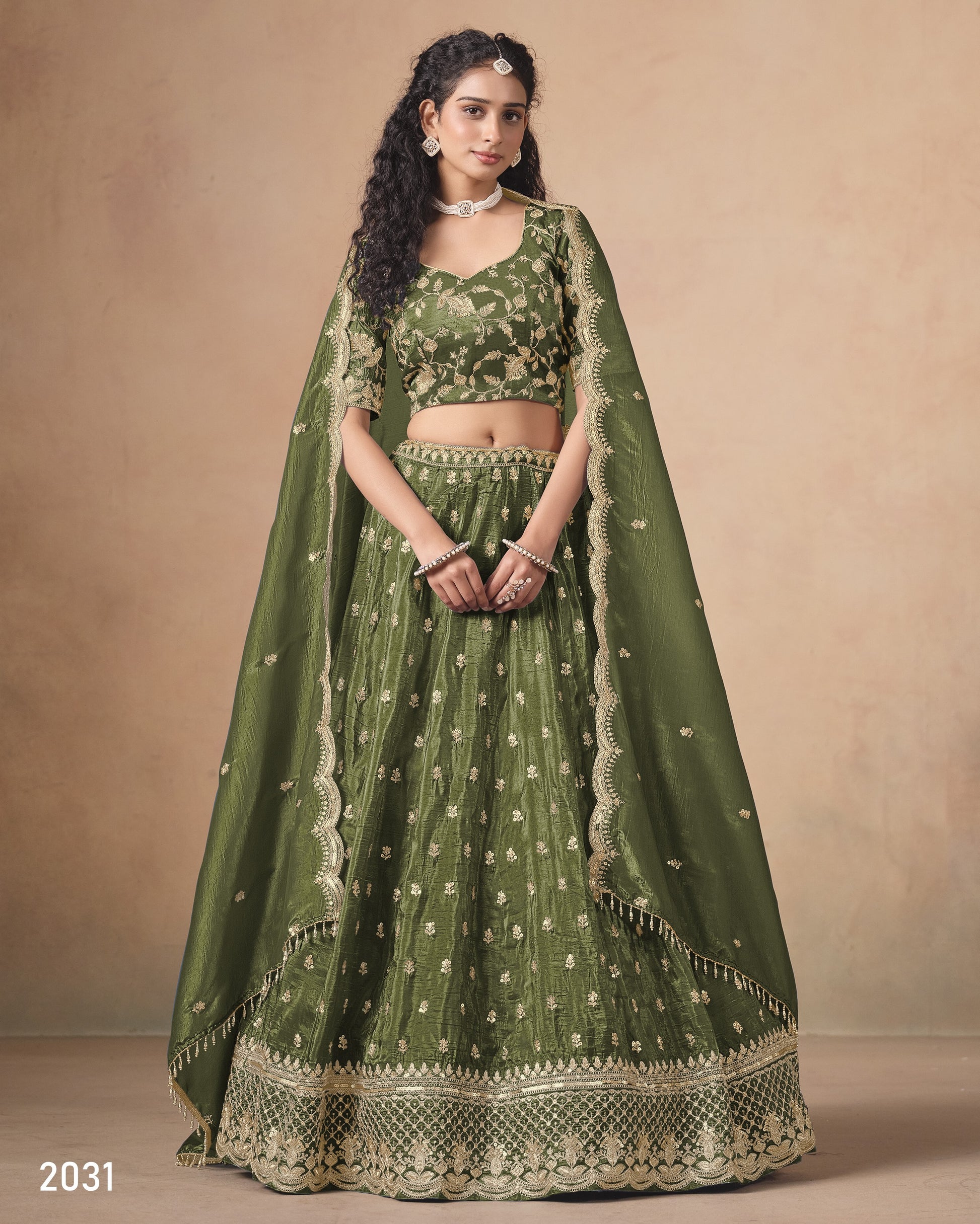 Woman wearing a green embroidered lehenga with a plain background