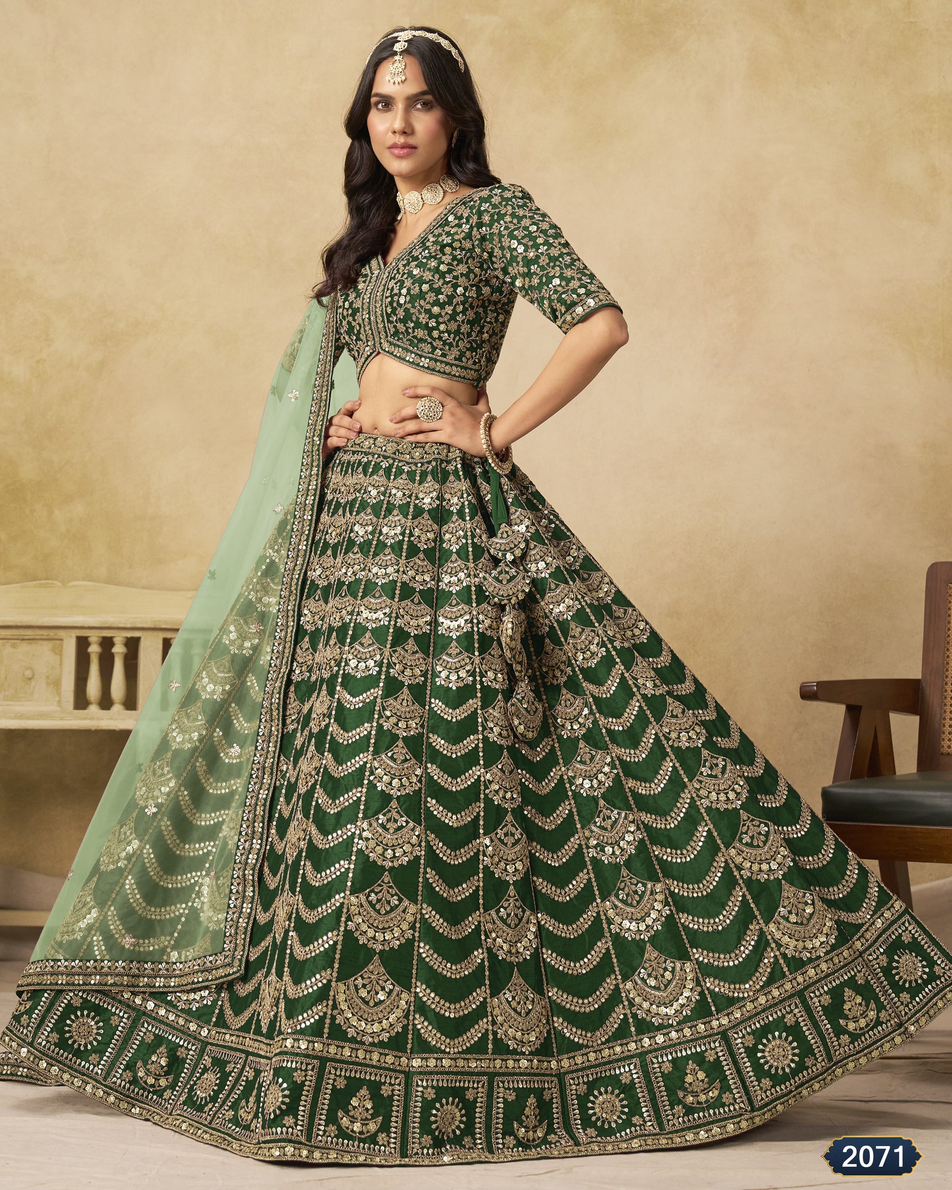 Woman wearing a green and silver embroidered traditional outfit with a beige background