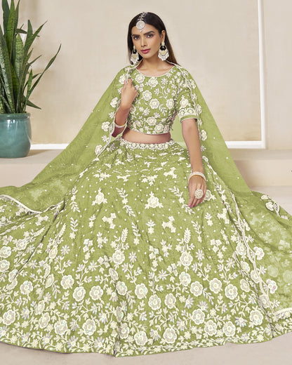 Woman wearing a green floral lehenga with a matching dupatta in an indoor setting.