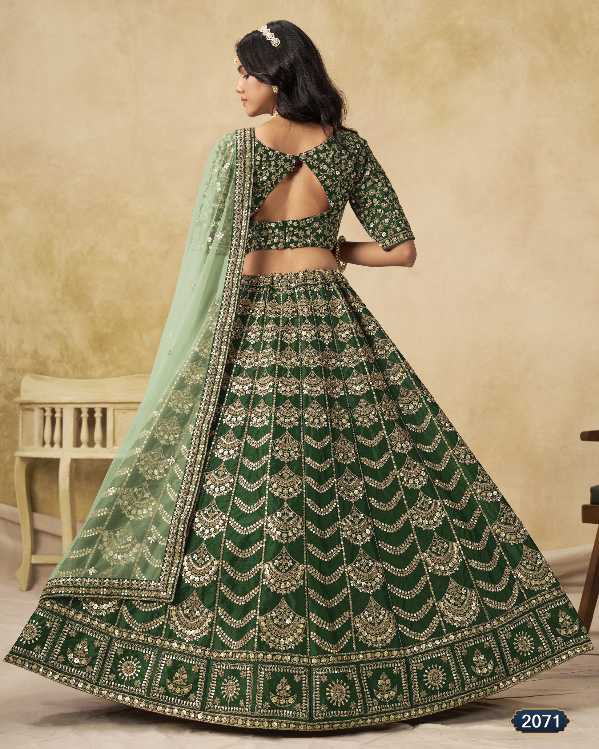 Woman wearing a green embroidered lehenga with a matching dupatta against a beige background