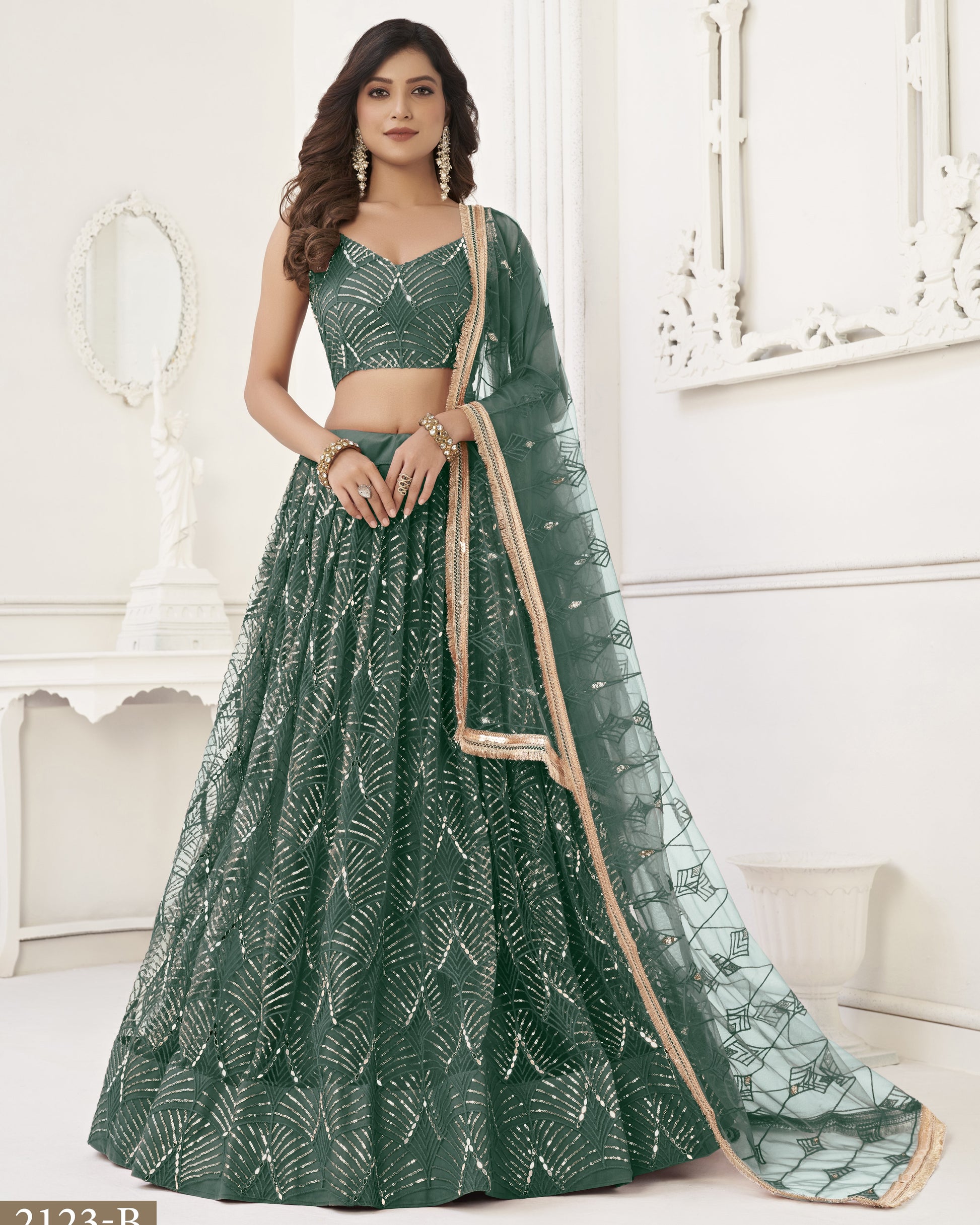 Woman wearing a green traditional outfit with a matching dupatta in a well-lit room.