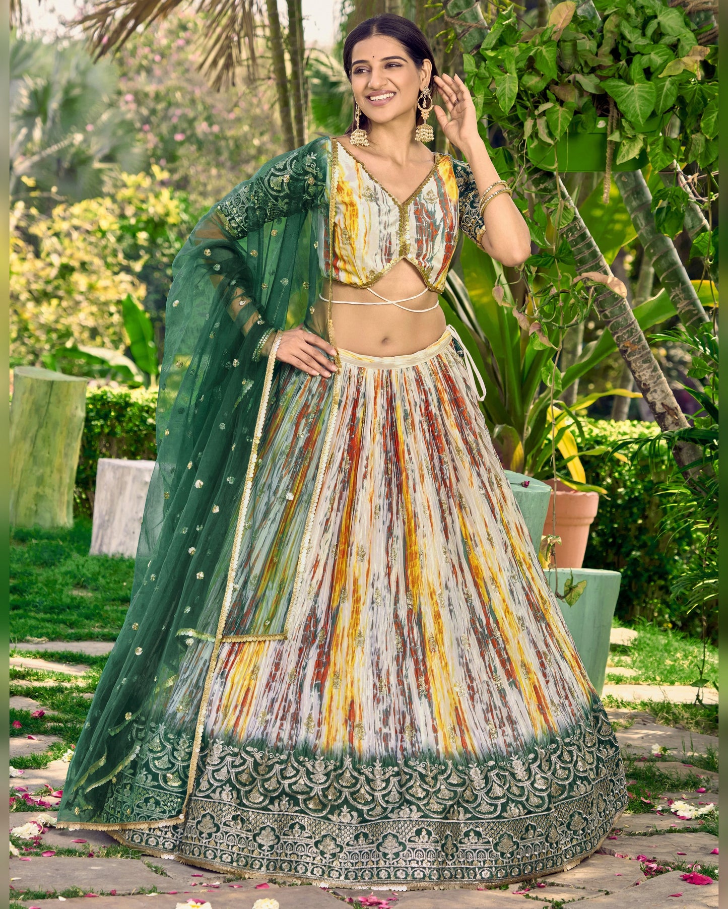 Woman in traditional outfit with green dupatta and colorful skirt in a garden setting