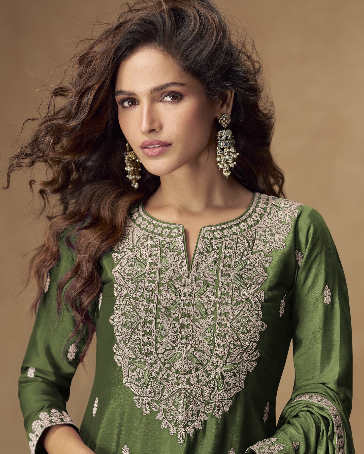 Woman wearing a green embroidered traditional outfit with a brown background
