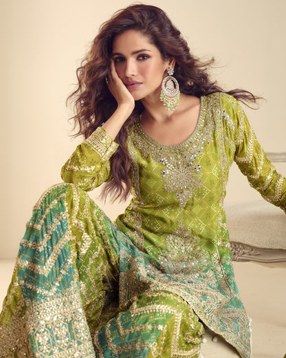 Woman wearing a green and gold embroidered traditional outfit with jewelry.