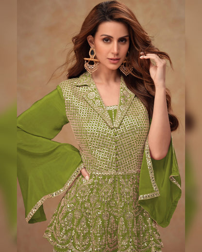 Woman wearing a green and silver embroidered outfit against a beige background