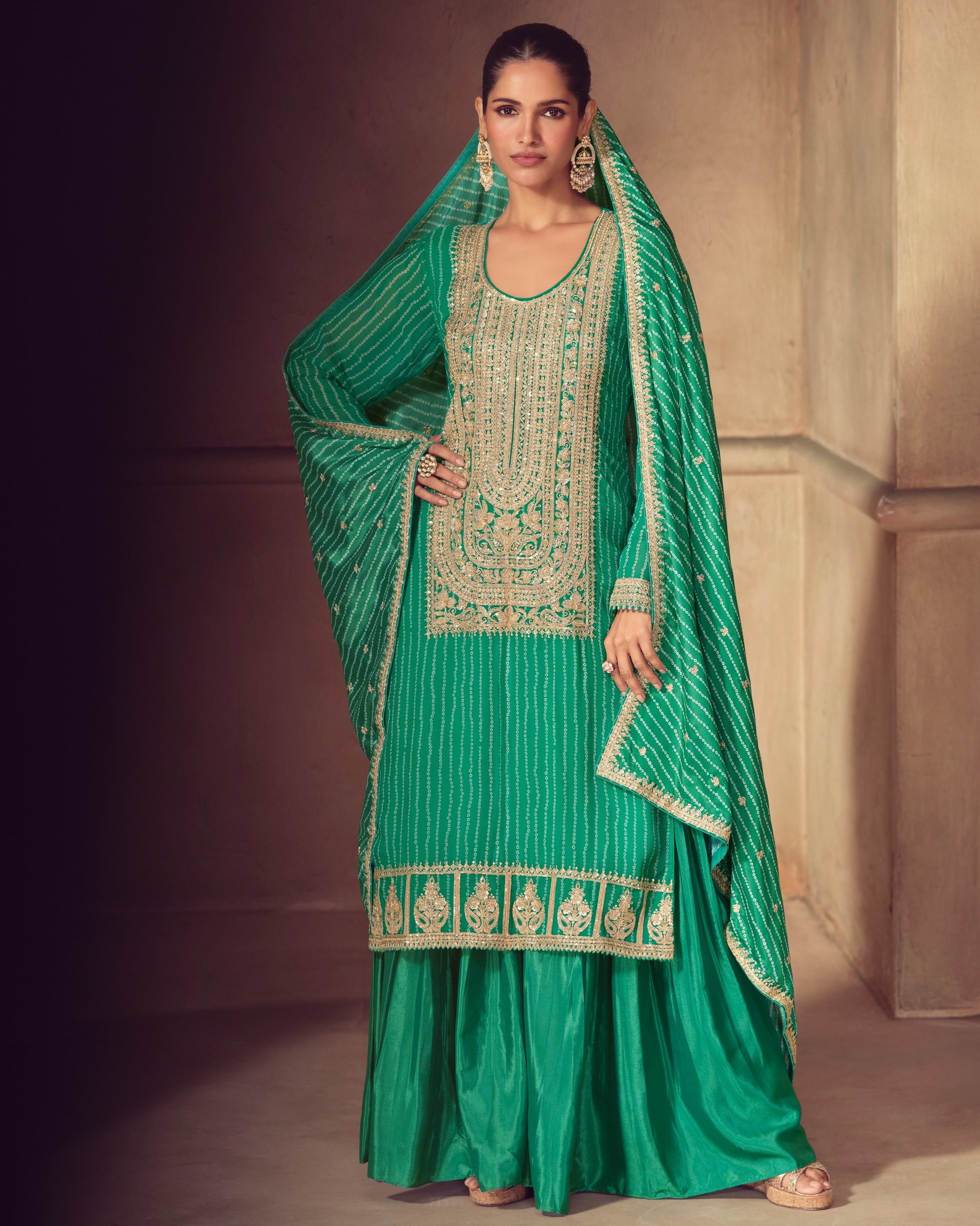 Woman wearing a green traditional outfit with embroidery in an indoor setting