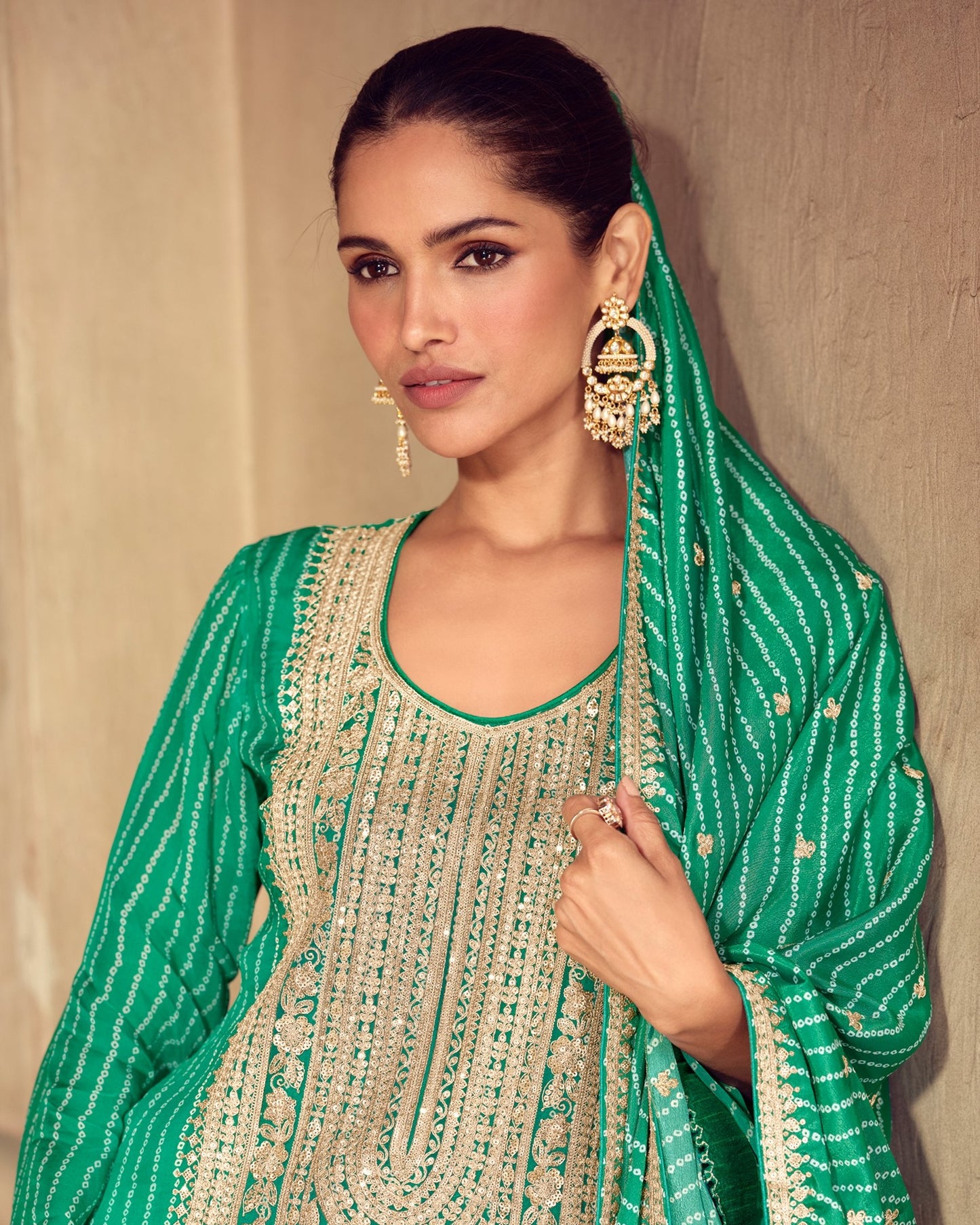 Woman wearing a green and gold traditional outfit with a matching headscarf.