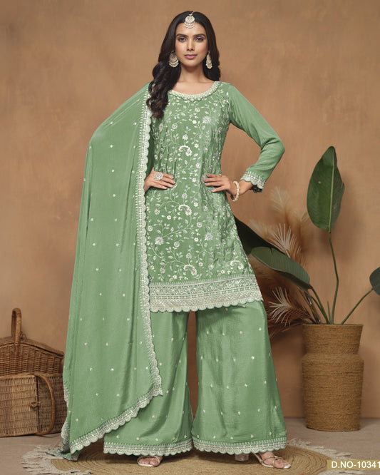 Woman wearing a green traditional outfit with a matching dupatta against a brown background
