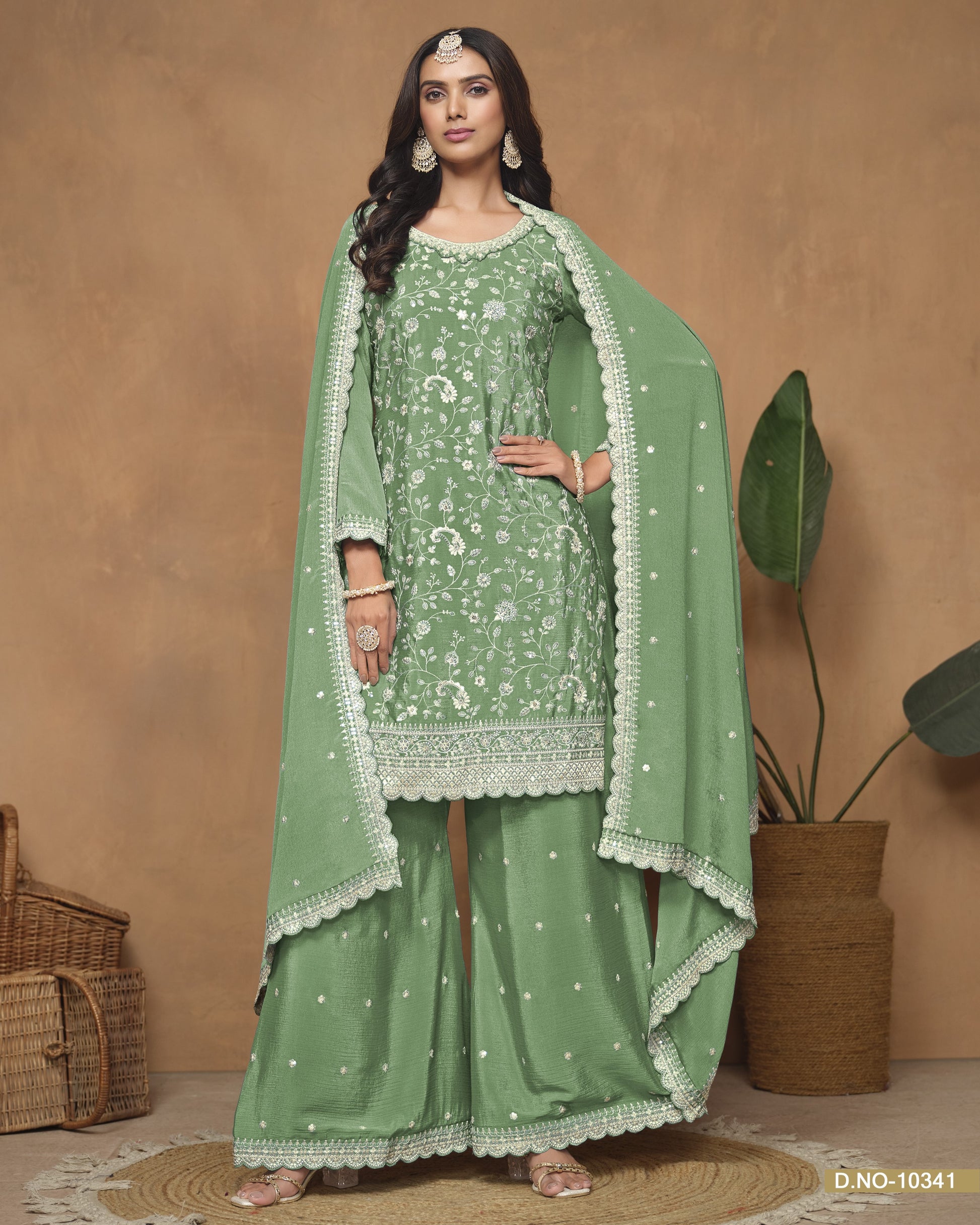 Woman wearing a green traditional outfit with a matching dupatta against a beige background