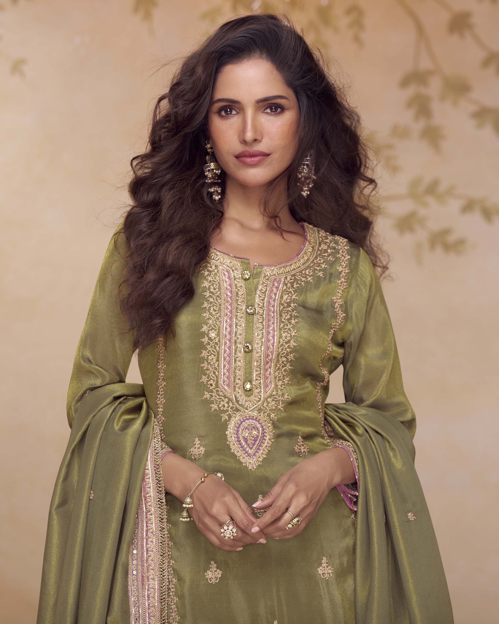 Woman wearing a green embroidered traditional outfit with a beige background