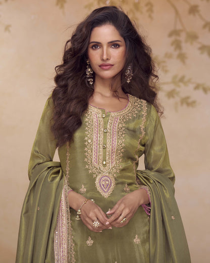 Woman wearing a green embroidered traditional outfit with a beige background