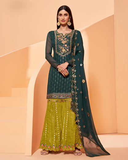 Woman wearing a green and yellow traditional outfit with intricate patterns on a peach background