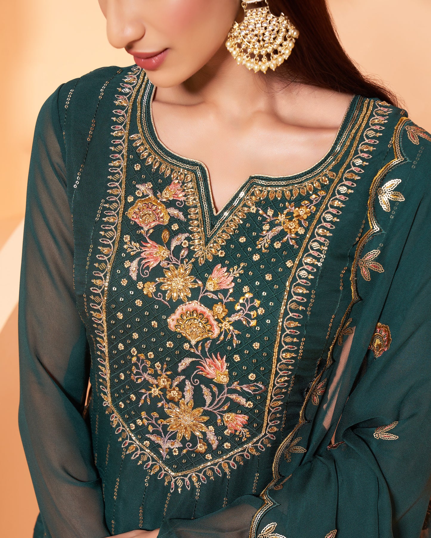 Green embroidered garment with gold detailing on a beige background
