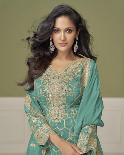 Woman wearing a green and gold embroidered traditional outfit against a beige background