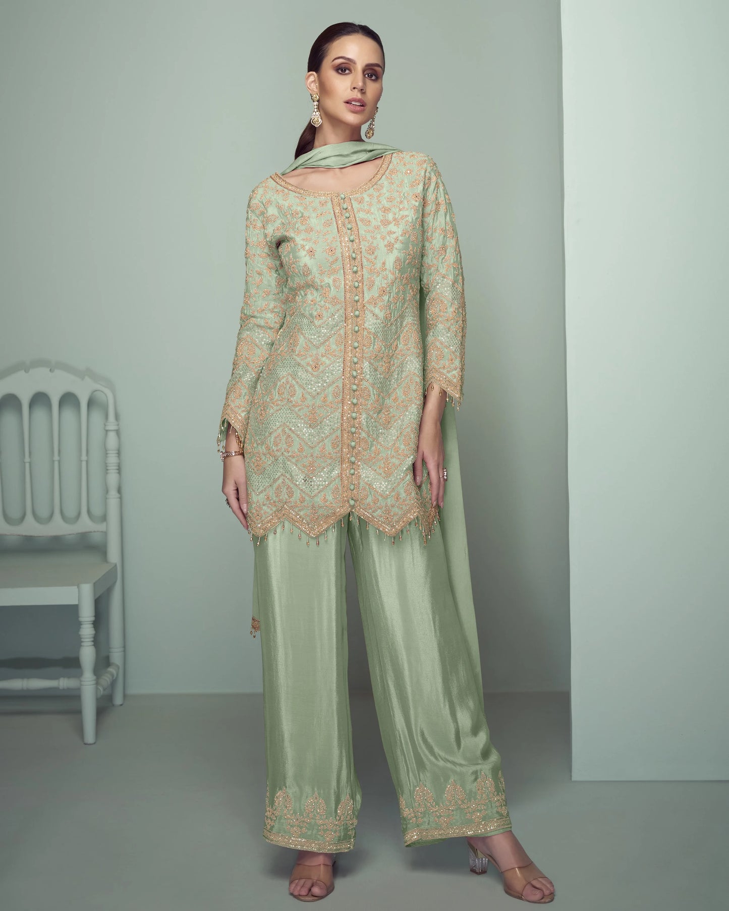 Woman wearing a light green embroidered outfit in a minimalistic setting