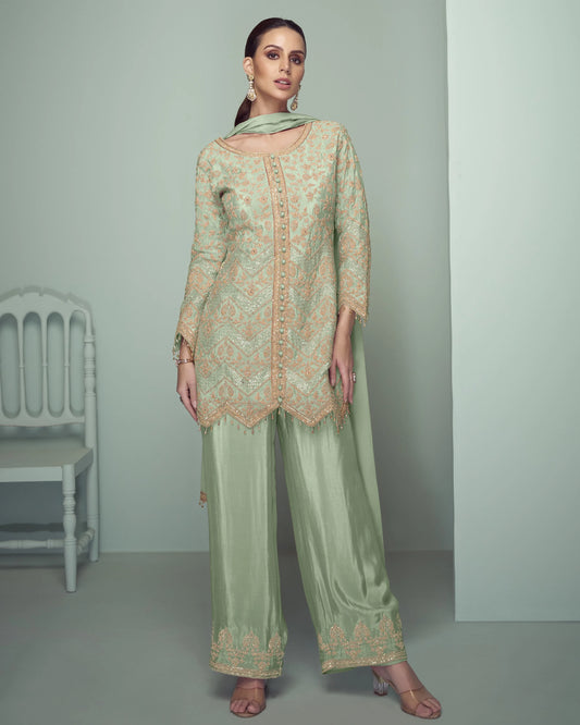 Woman wearing a light green embroidered outfit in a minimalistic setting