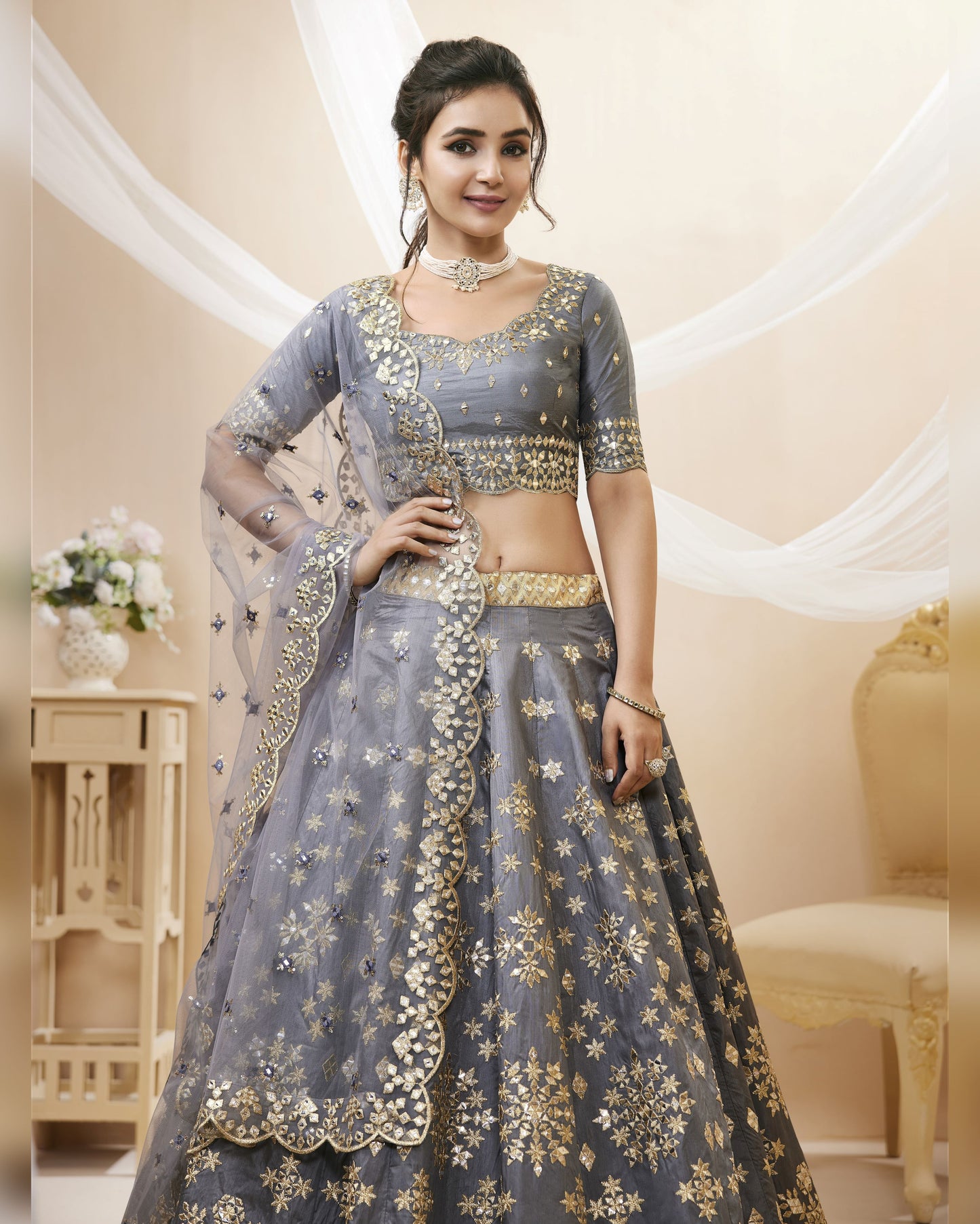 Woman in a gray and gold traditional outfit with a decorative background