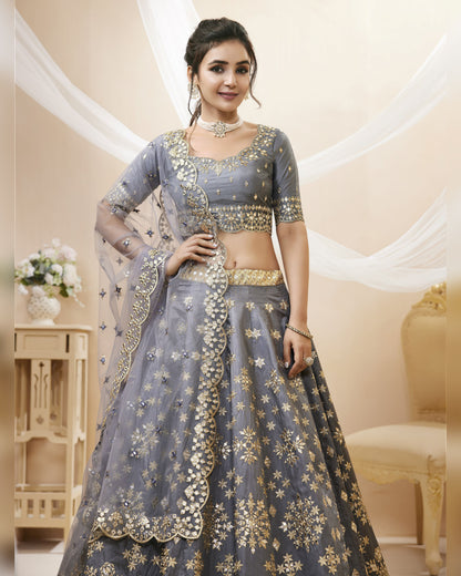 Woman in a gray and gold traditional outfit with a decorative background