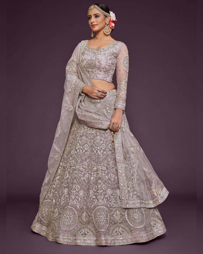 Woman wearing a silver embroidered lehenga with a matching blouse on a dark purple background
