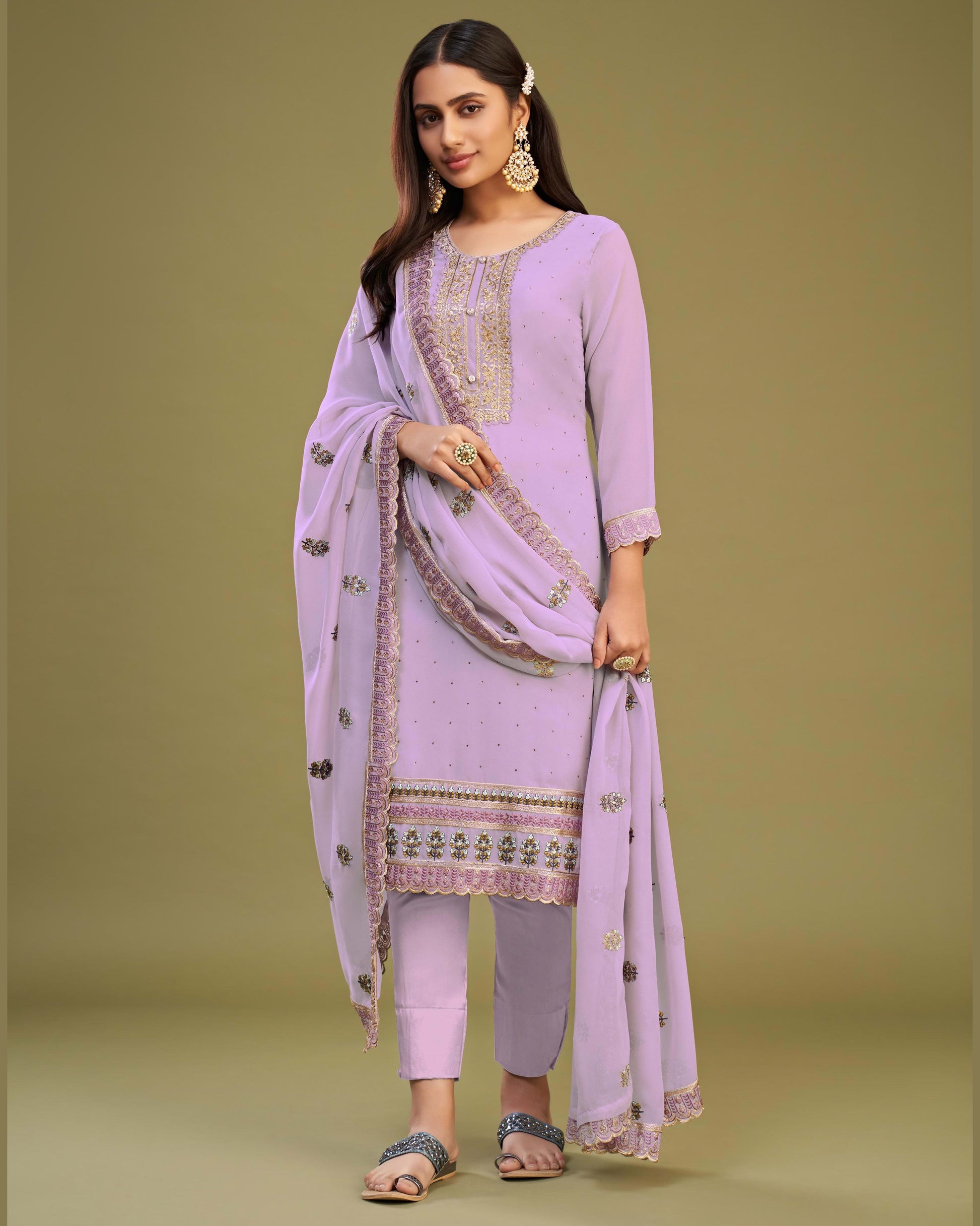 Woman wearing a lavender traditional outfit with a matching dupatta on a green background
