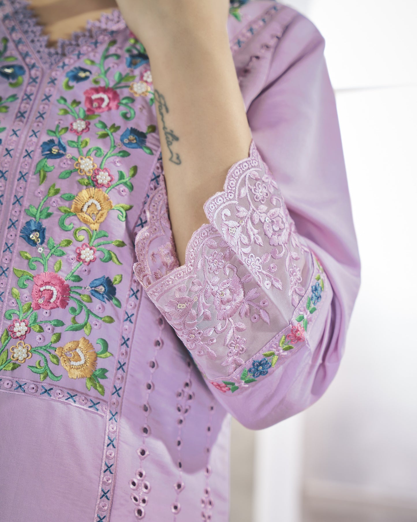 Close-up of a person wearing a light purple embroidered blouse with floral patterns.