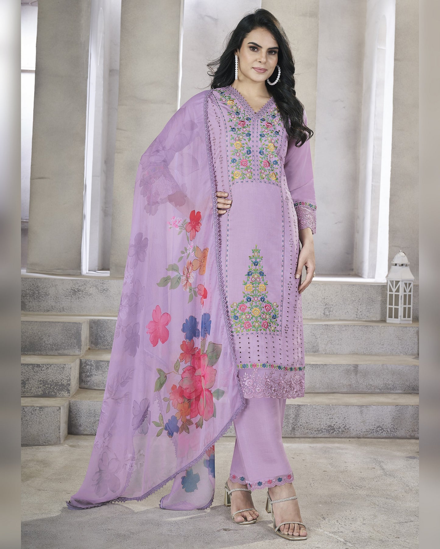 Woman wearing a lavender embroidered outfit with a floral dupatta in a neutral setting.