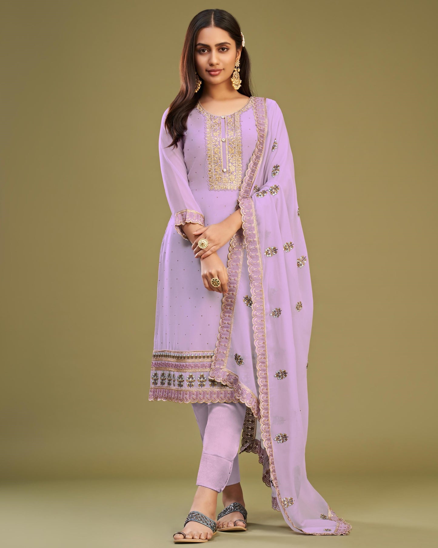 Woman wearing a lavender traditional outfit with a matching dupatta on a green background