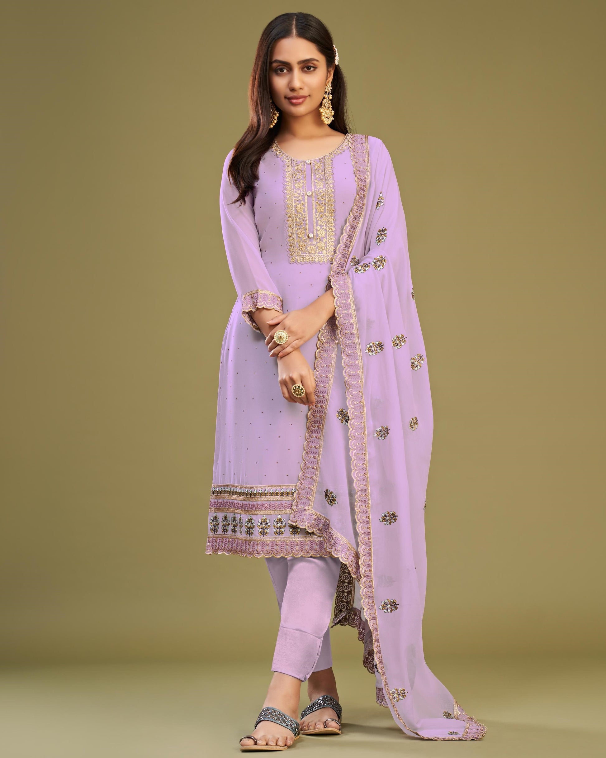Woman wearing a lavender traditional outfit with a matching dupatta on a green background