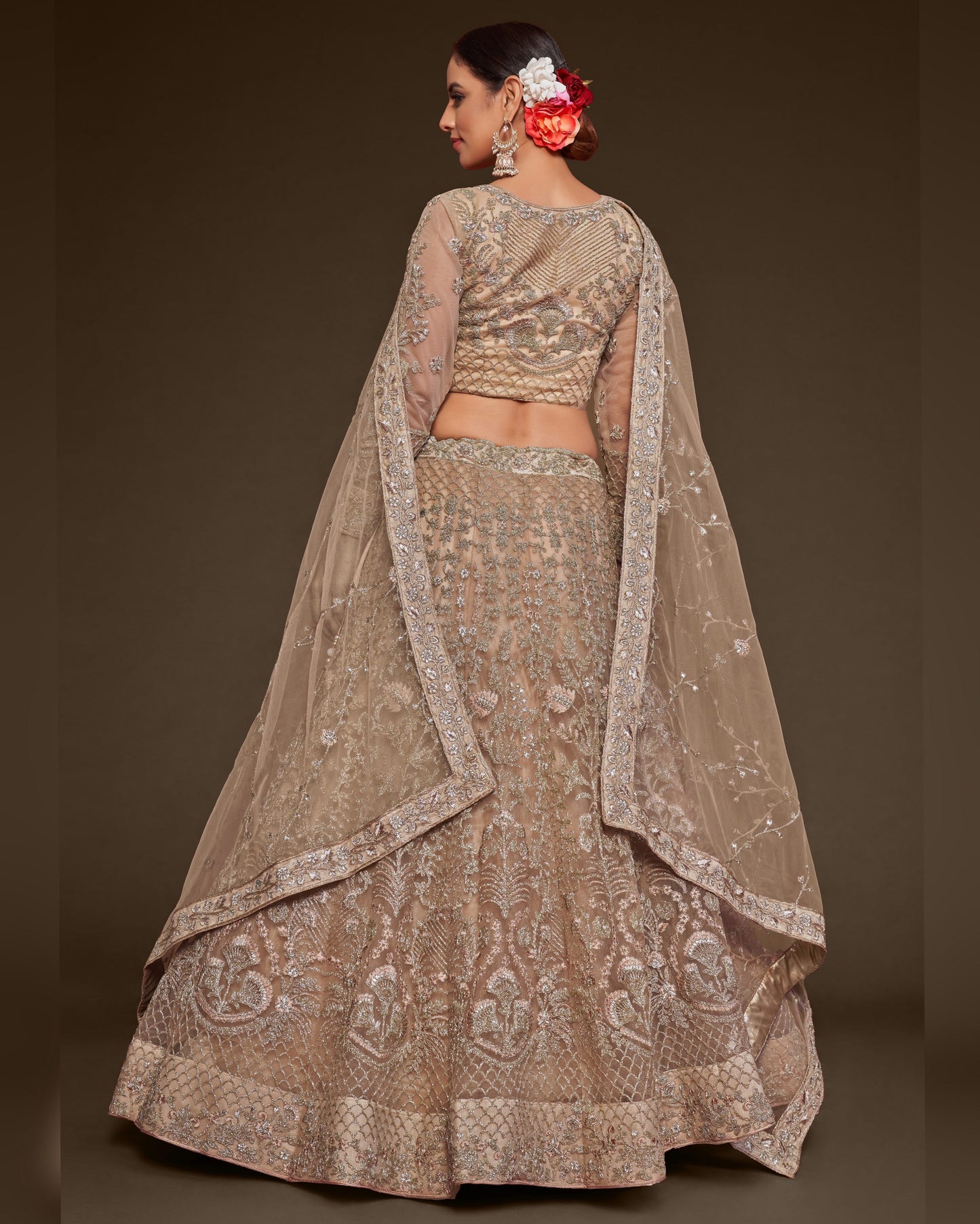 Woman wearing a traditional embroidered lehenga with a plain background