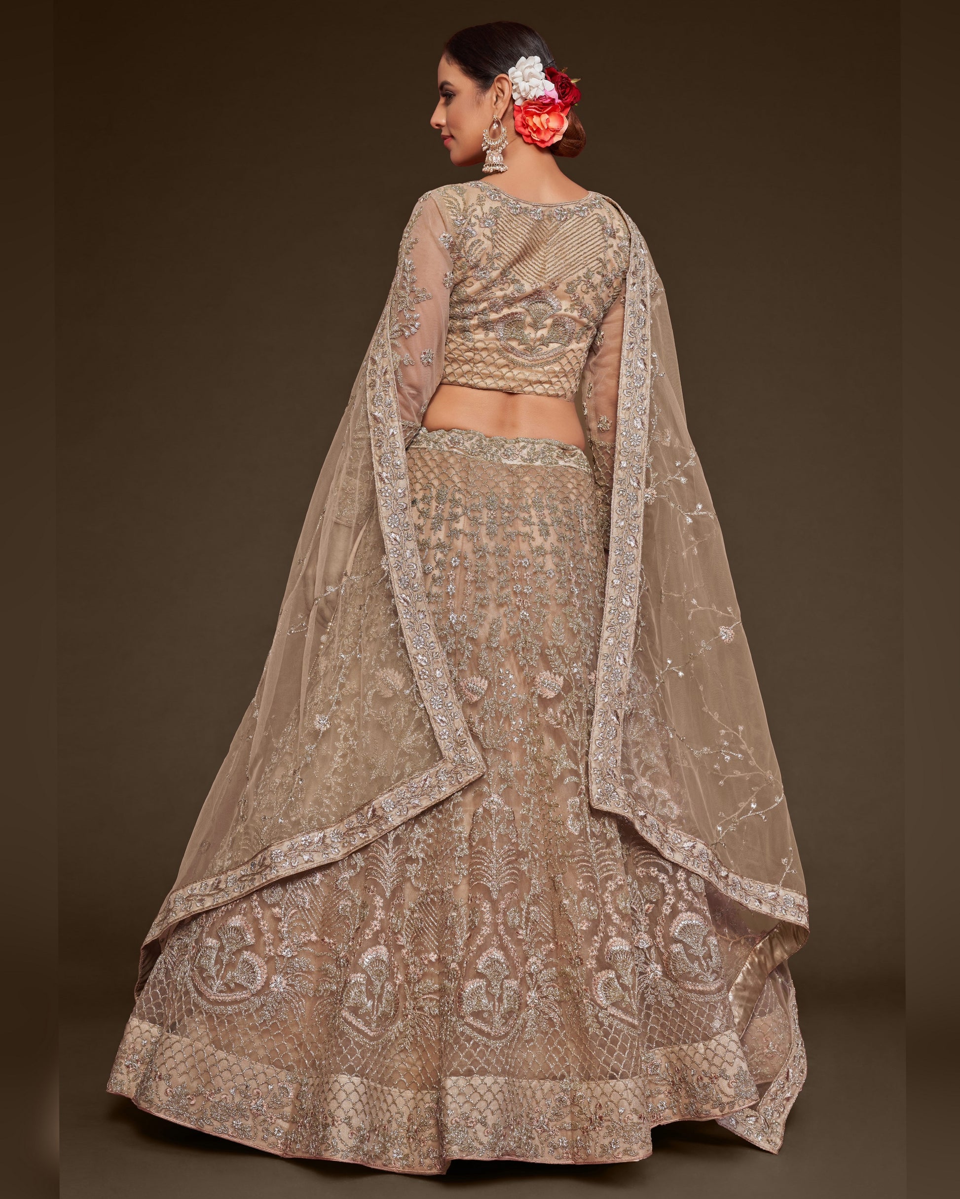 Woman wearing a traditional embroidered lehenga with a plain background