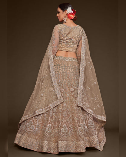 Woman wearing a traditional embroidered lehenga with a plain background