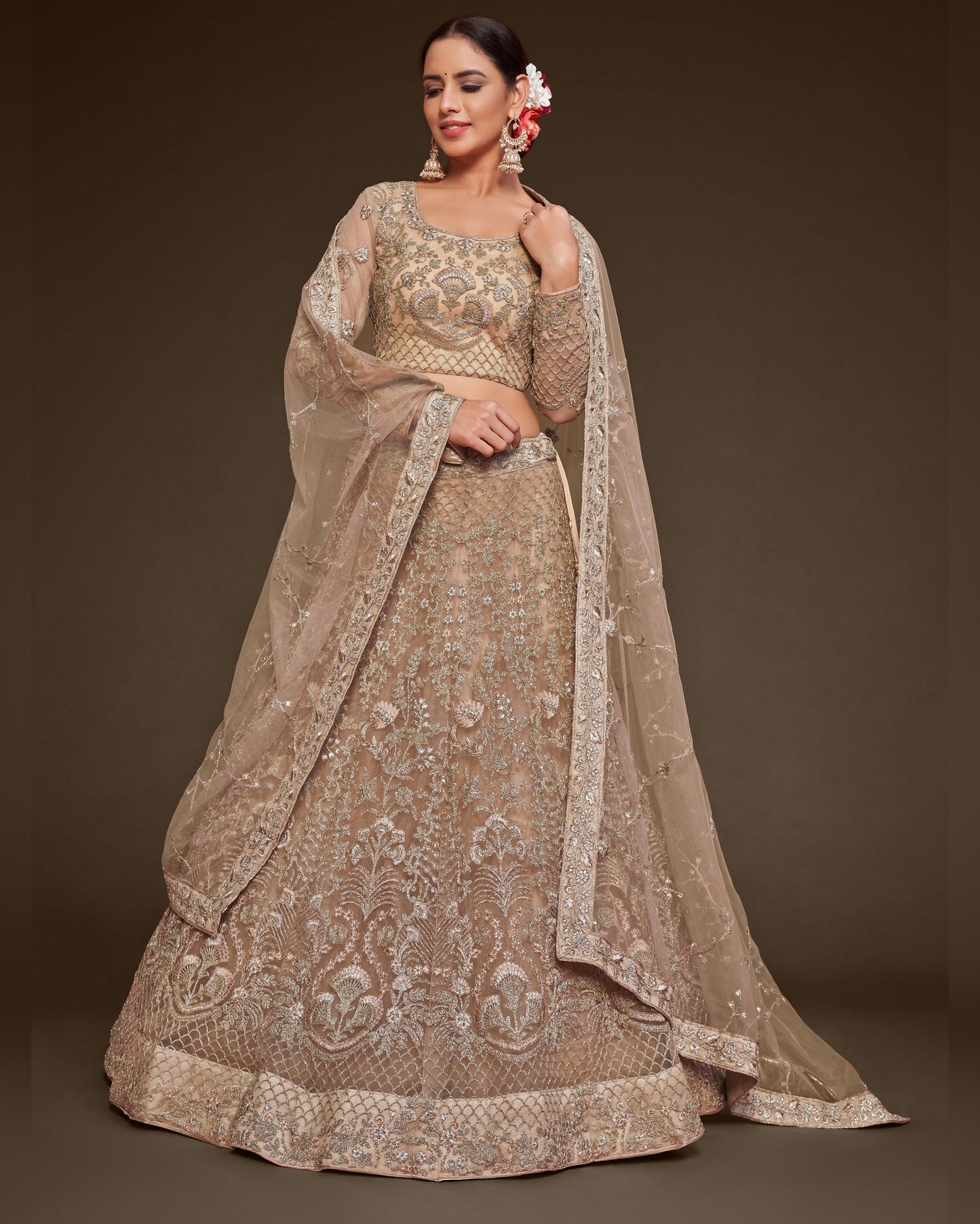 Woman wearing a beige embroidered traditional outfit with a matching dupatta on a dark background