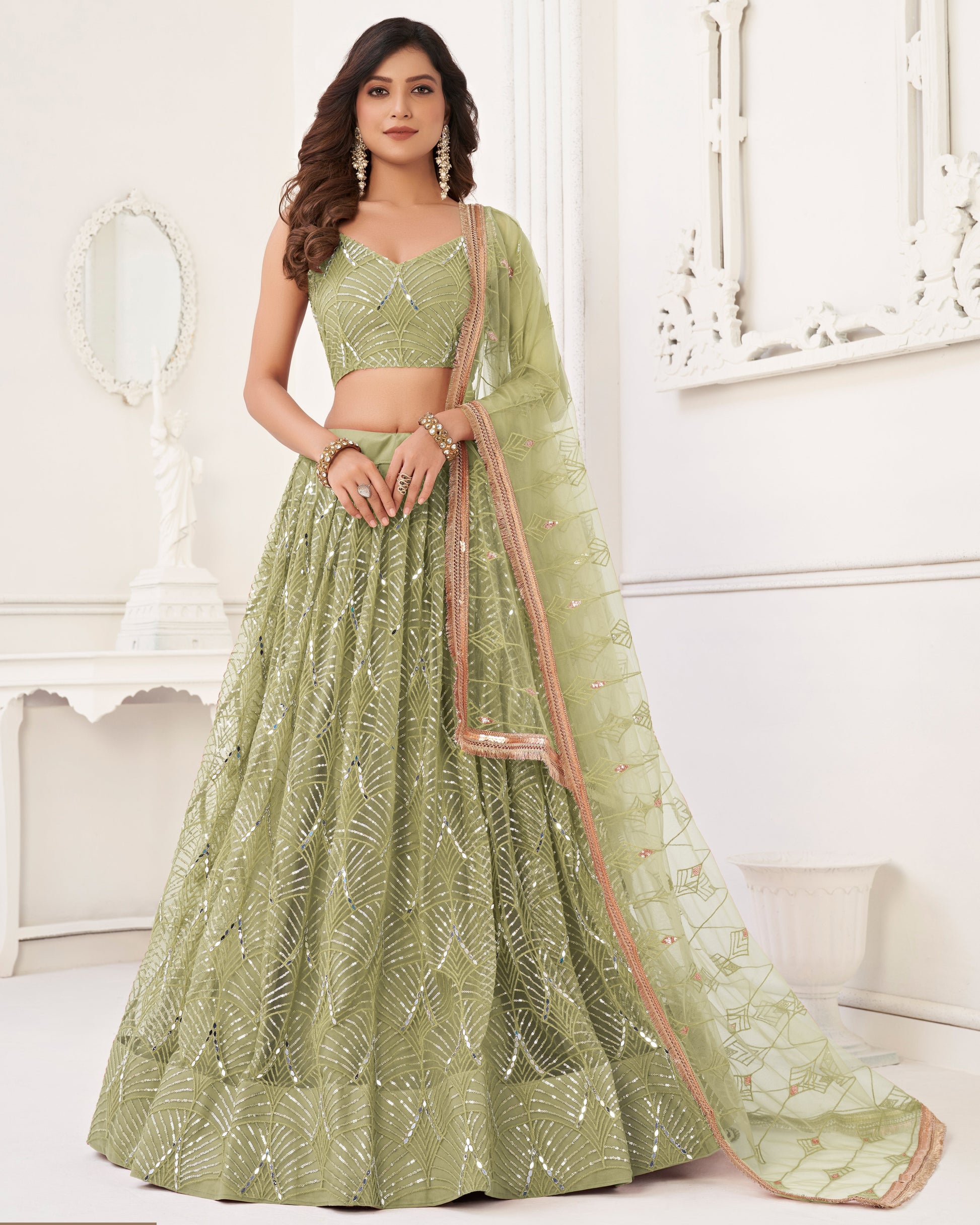 Woman wearing a green embroidered lehenga in an indoor setting