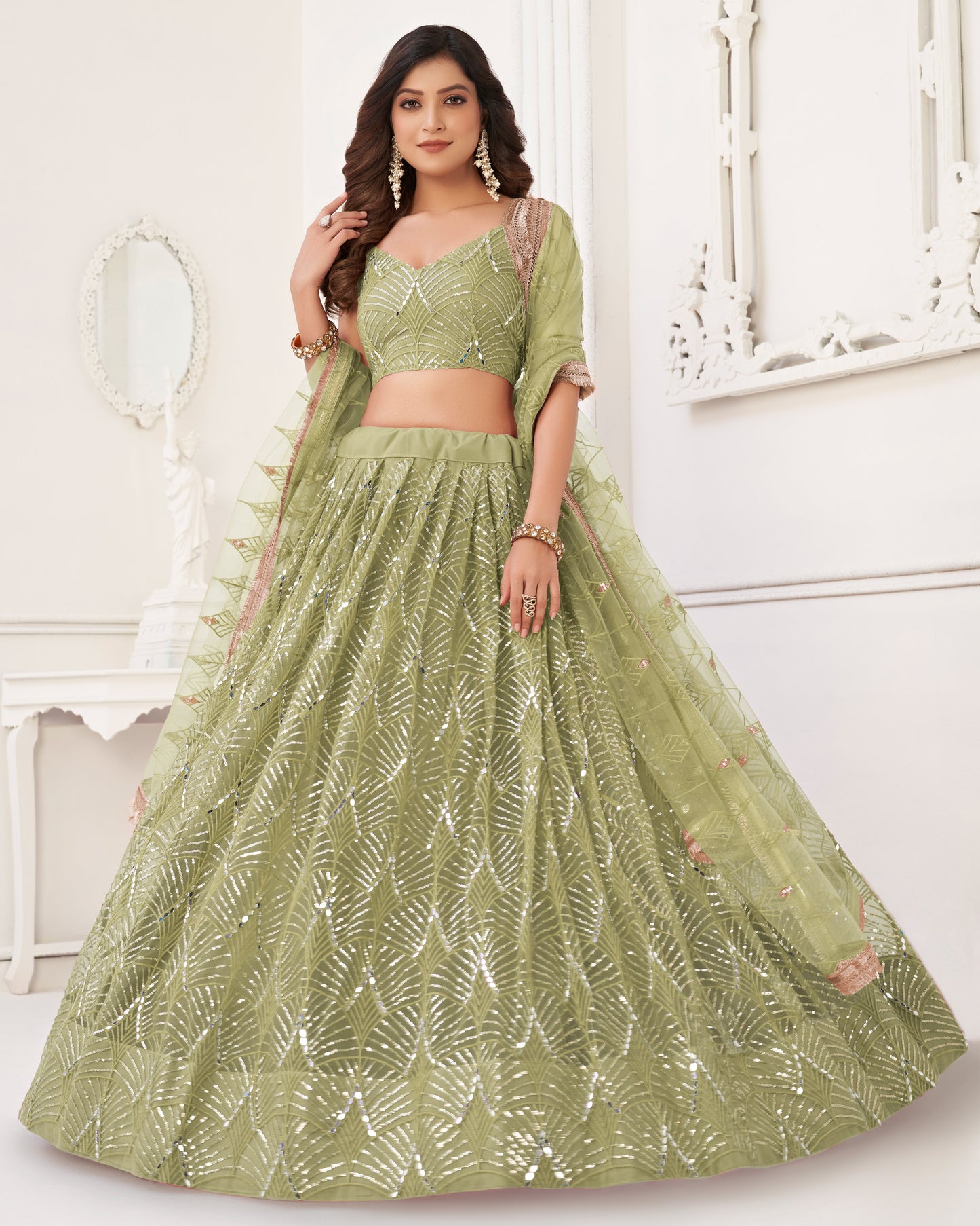 Woman wearing a green embroidered lehenga with a white background