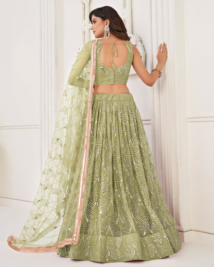Woman wearing a green embroidered lehenga with a white background