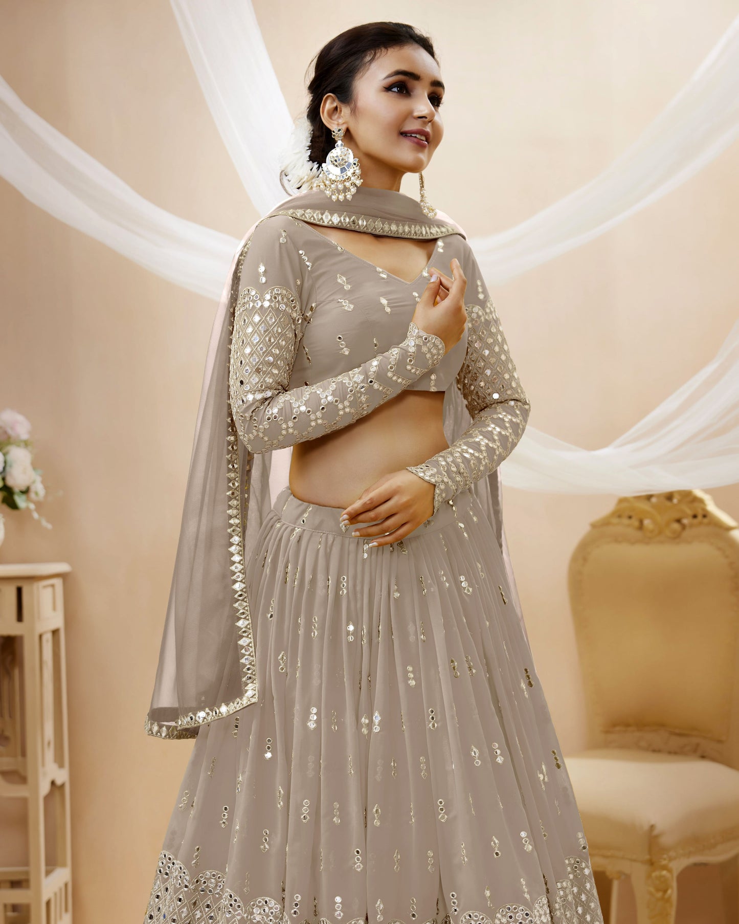 Woman wearing a gray traditional outfit with intricate designs in a softly lit room.